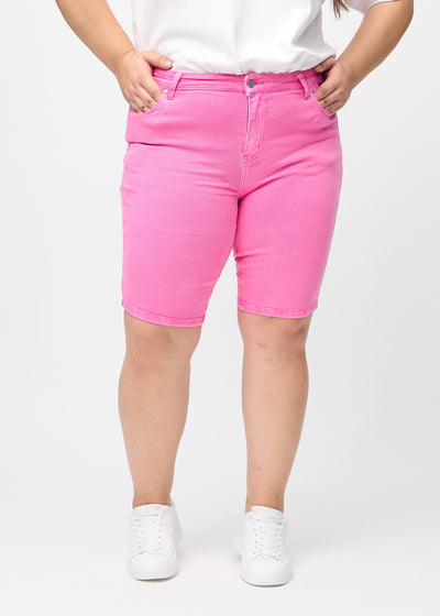 Lyserøde skinny middle shorts, modelnavn Flamingos, som sidder tæt til låret og slutter lige over knæet på en plus-size model, set forfra.