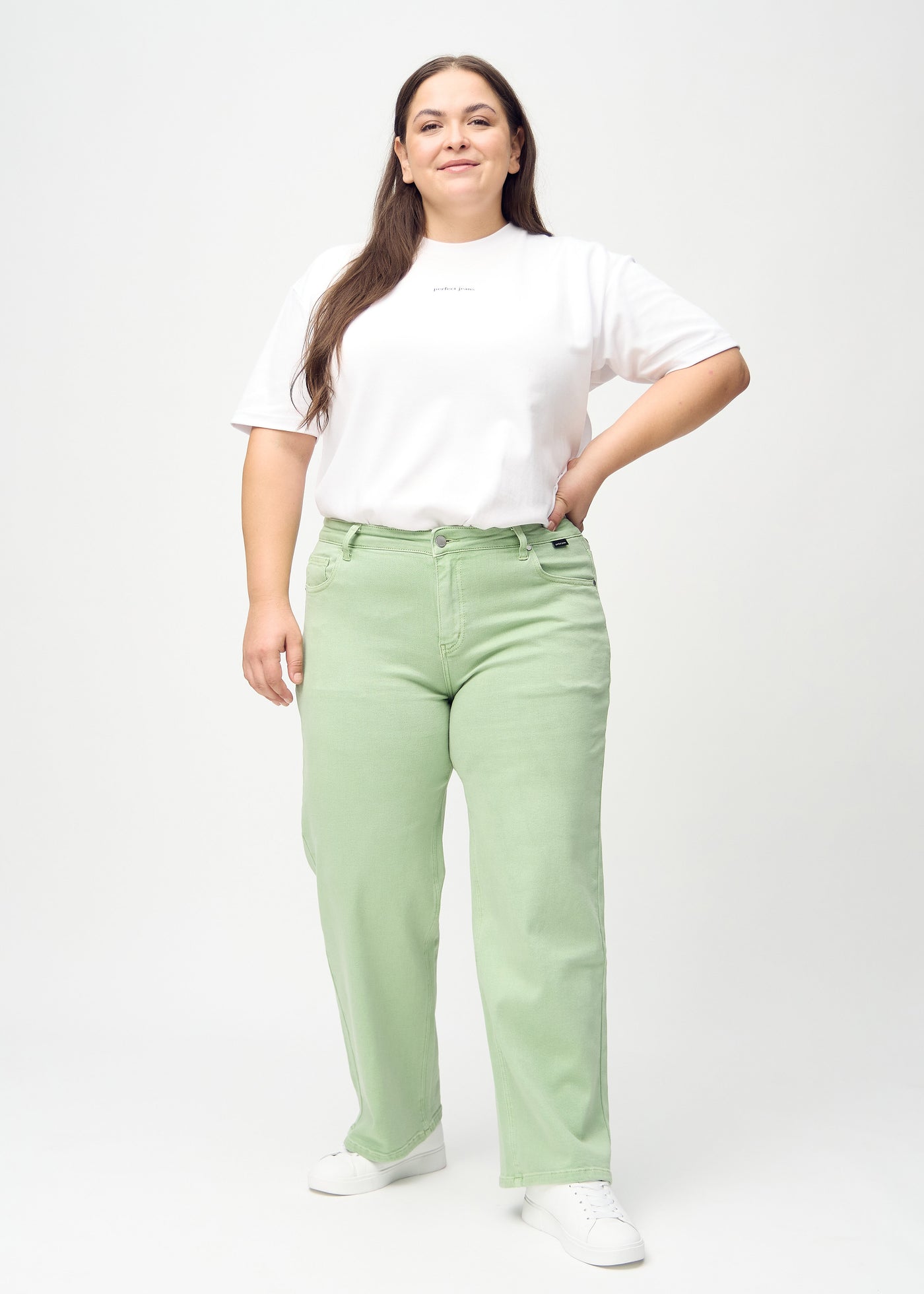 Fuldt billede af en plus-size model i lysegrønne loose jeans.
