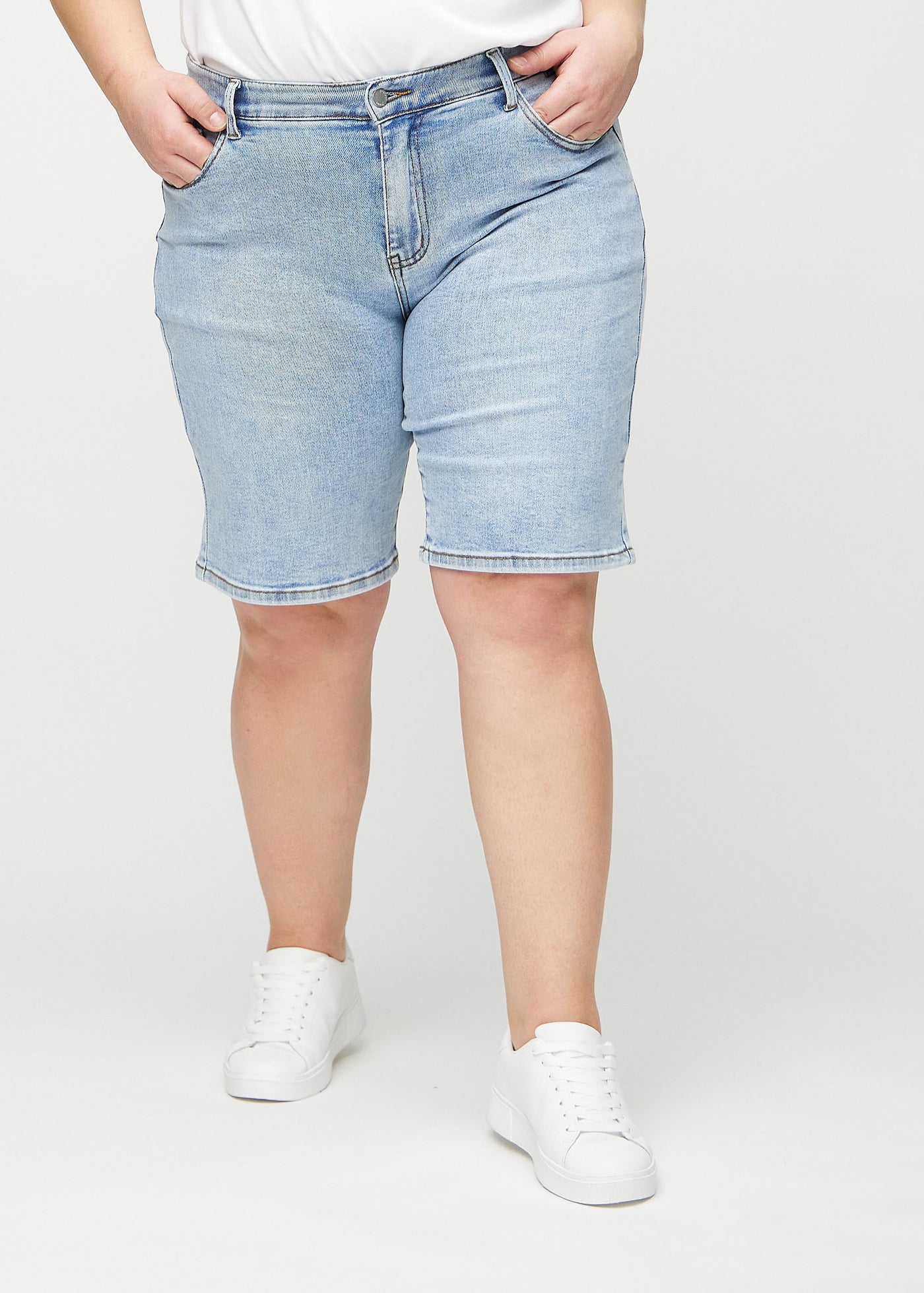 Lys denim regular middle shorts, modelnavn Waves, som går lige ned langs benet og slutter lige over knæet på en plus-size model, set forfra.