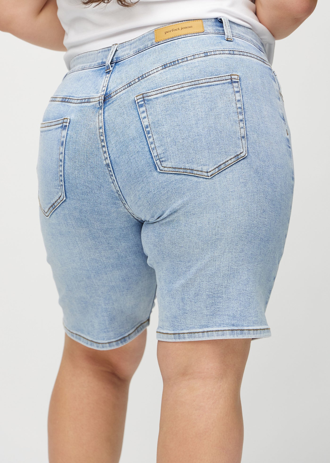 Lys denim regular middle shorts set bagfra tæt på en plus-size model for at vise detaljer.