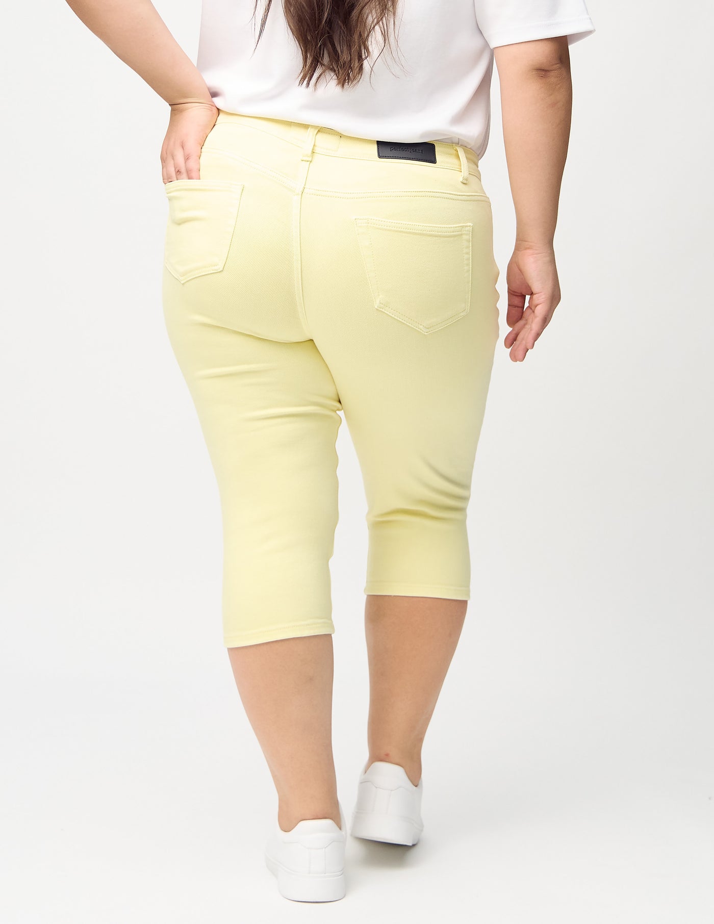  Lysegule skinny capris set bagfra på en plus-size model, så man kan se hele produktet.