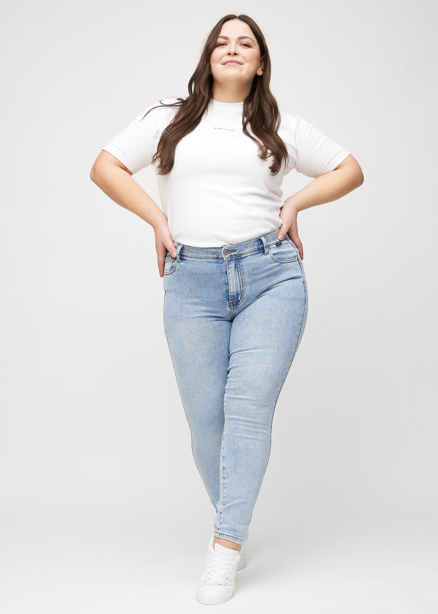 Fuldt billede af en plus-size model i lys denim skinny jeans.