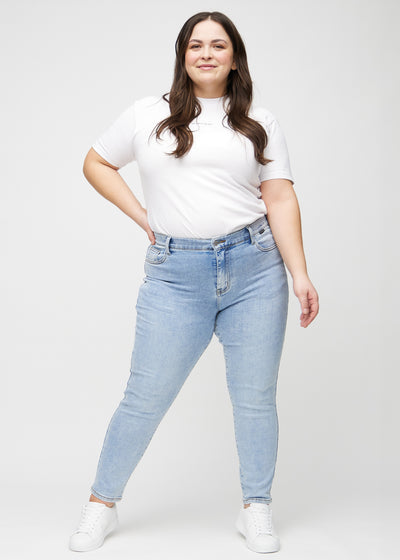 Fuldt billede af en plus-size model i lys denim slim jeans.