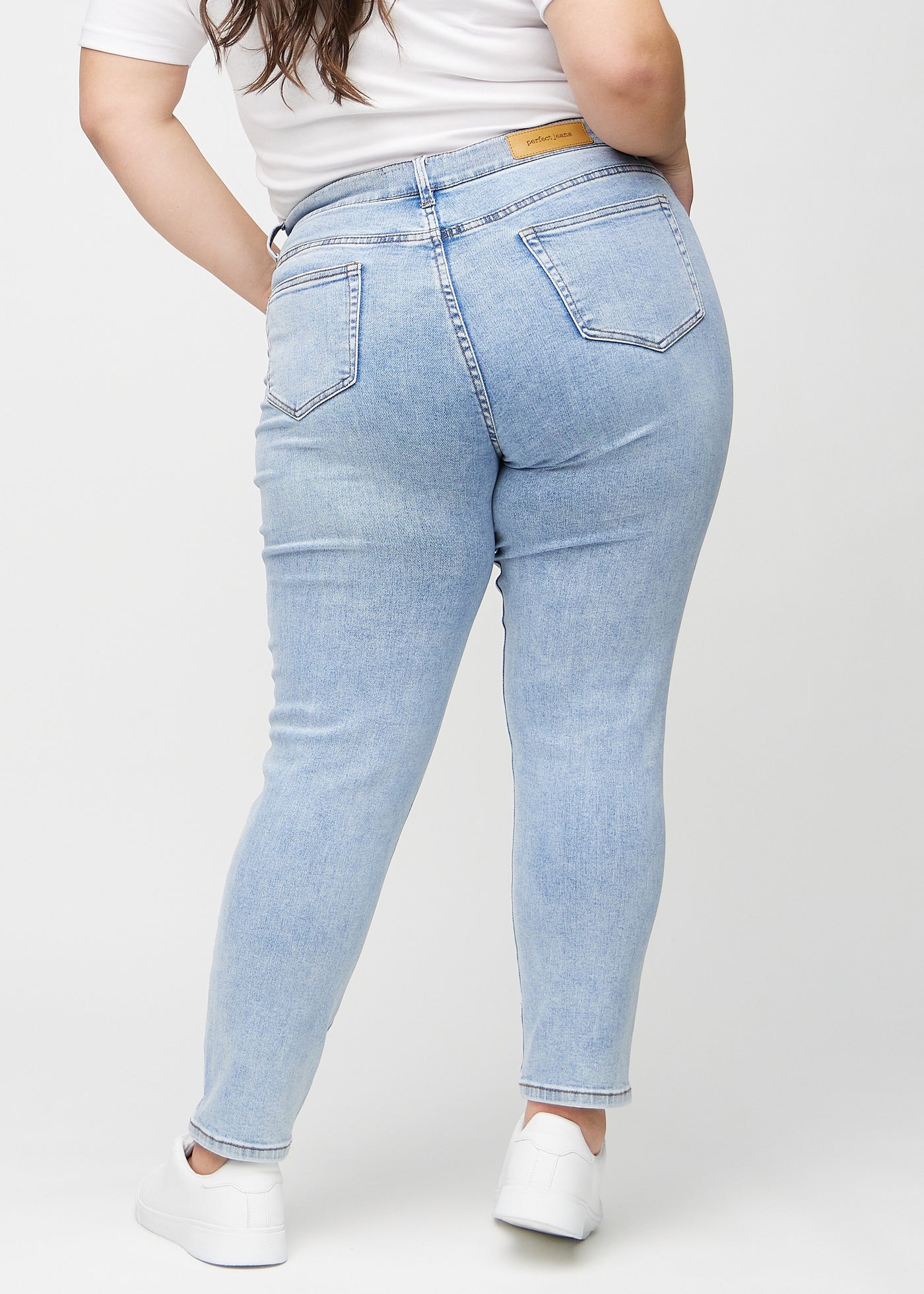 Lys denim slim jeans set bagfra på en plus-size model, så man kan se hele produktet.
