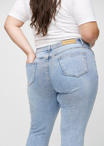 Lys denim slim jeans set bagfra tæt på en plus-size model for at vise detaljer.