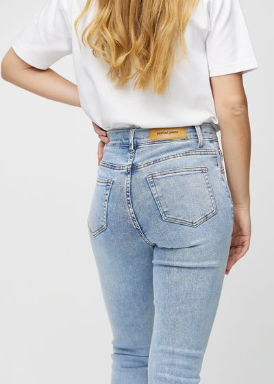Lys denim slim jeans set bagfra tæt på for at vise detaljer.