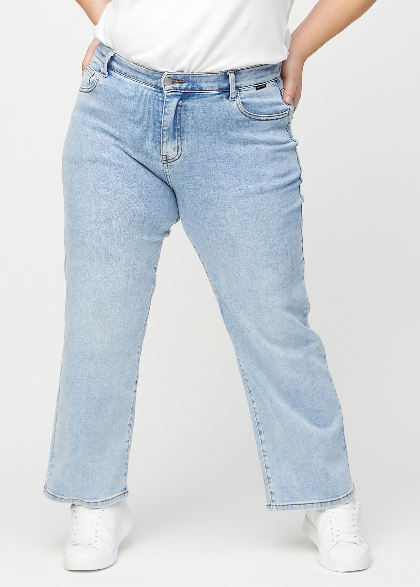 Lys denim loose jeans, modelnavn Waves, som er løstsiddende med masser af vidde i benene på en plus-size model, set forfra.