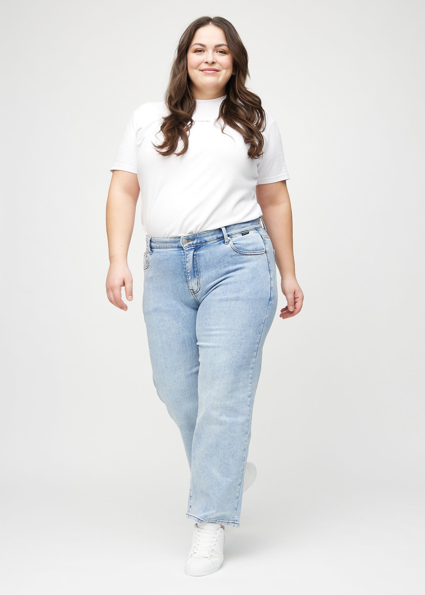 Fuldt billede af en plus-size model i lys denim loose jeans.