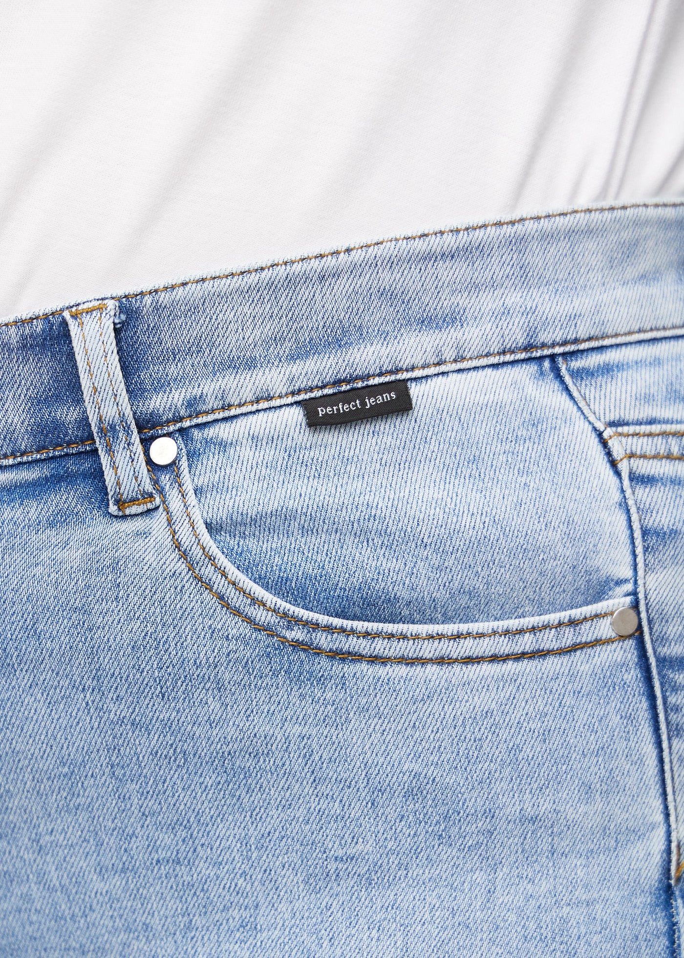 Forlommen på et par lys denim jeans, hvor man kan se logoet på en plus-size model.