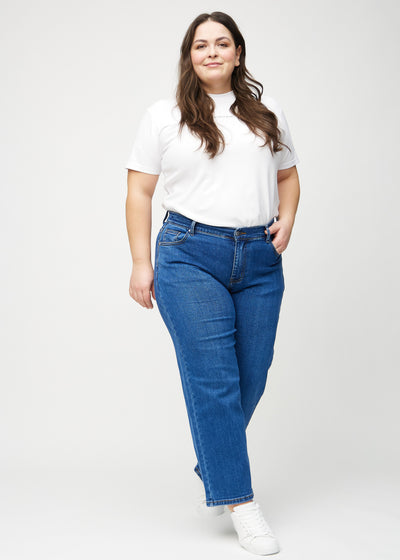 Plus-size model går ind i billedet, strækker i jeansene, viser dem frem ved at dreje rundt, og forlader derefter billedet.